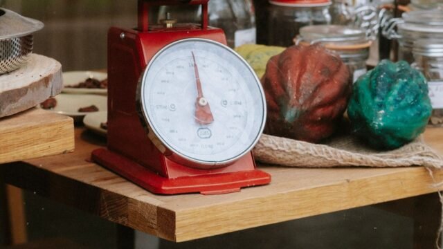 Analoge keukenweegschaal retro: rode vintage weegschaal met metalen schaal in een keuken
