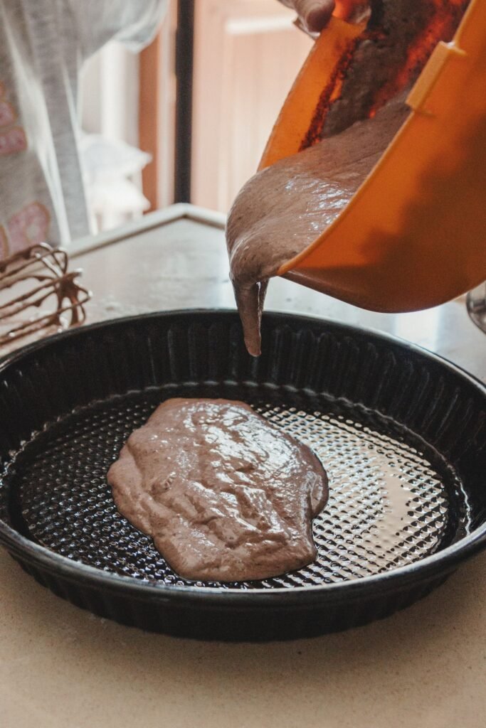 Bakvormen BPA vrij: chocoladebeslag wordt in een ronde metalen bakvorm gegoten