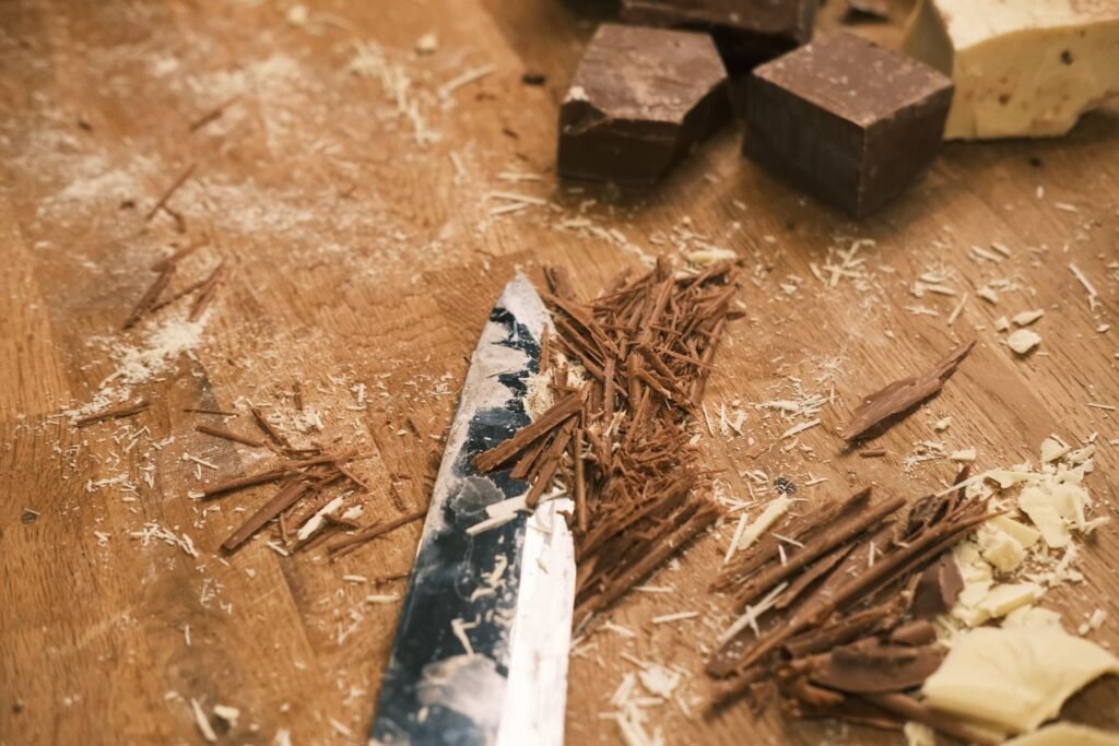 Chocolade schaafsel bakken: chocoladekrullen en een mes op een houten plank met stukken chocolade