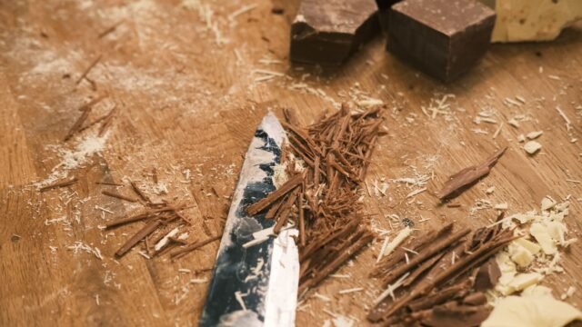 Chocolade schaafsel bakken: chocoladekrullen en een mes op een houten plank met stukken chocolade