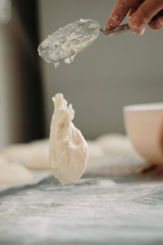 Deegmenger handmatig: brooddeeg wordt met een lepel gemengd op een met bloem bestoven werkblad