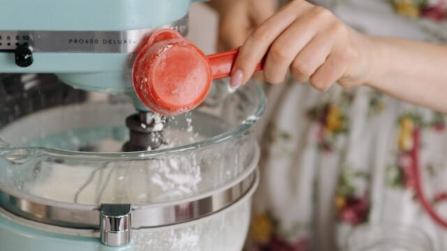 Deegmixer kopen: ingrediënten worden toegevoegd aan een lichtblauwe keukenrobot