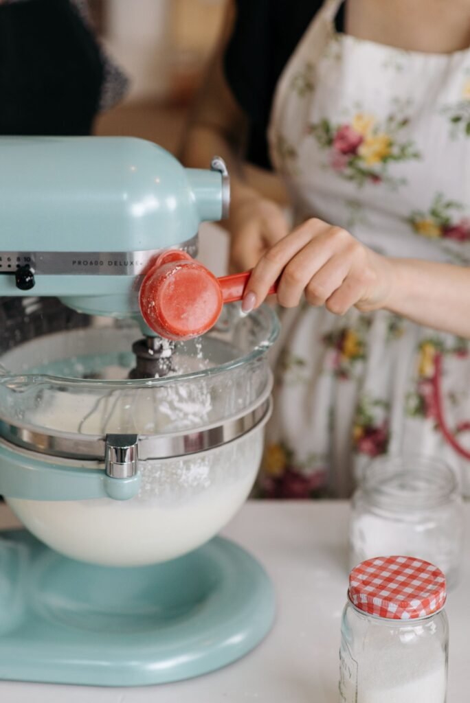Deegmixer kopen: ingrediënten worden toegevoegd aan een lichtblauwe keukenrobot