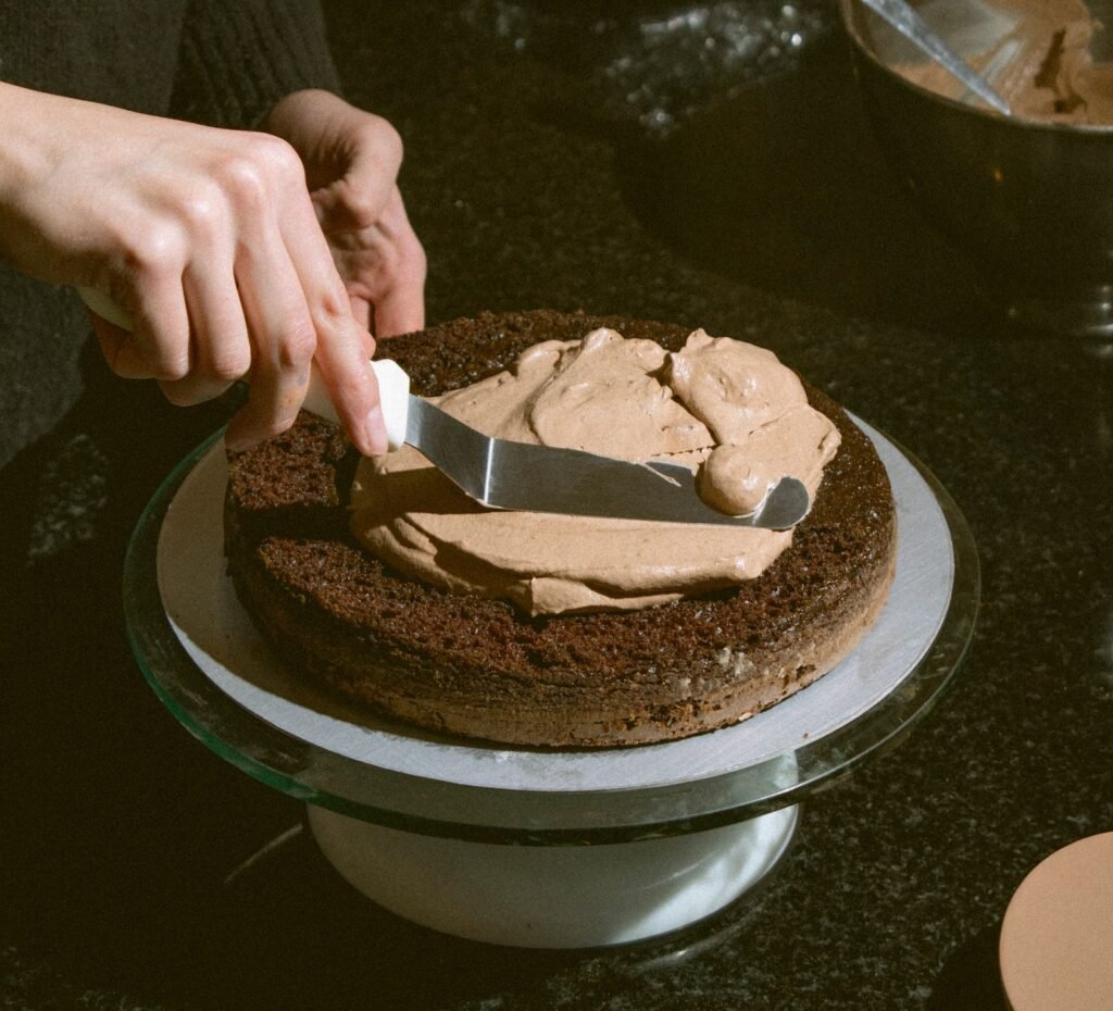 Draaiend taartplateau rvs: chocoladecrème wordt gladgestreken op een taart op een draaiplateau