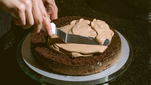 Draaiend taartplateau rvs: chocoladecrème wordt gladgestreken op een taart op een draaiplateau