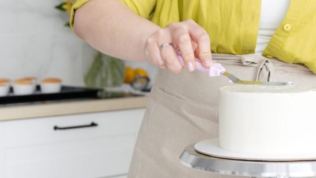 Draaiplateau taartdecoratie Aveve: vrouw versiert een witte taart op een draaiplateau in de keuken