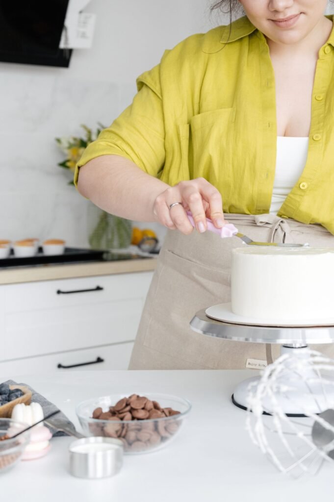 Draaiplateau taartdecoratie Aveve: vrouw versiert een witte taart op een draaiplateau in de keuken