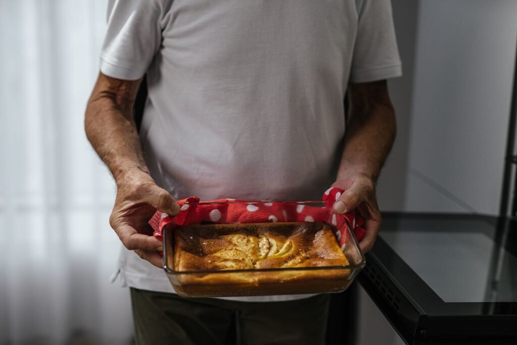 Glazen cakevorm ovenbestendig: man houdt een glazen ovenschaal met versgebakken taart vast