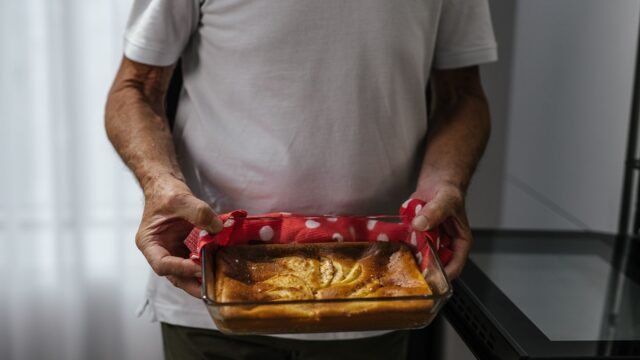 Glazen cakevorm ovenbestendig: man houdt een glazen ovenschaal met versgebakken taart vast
