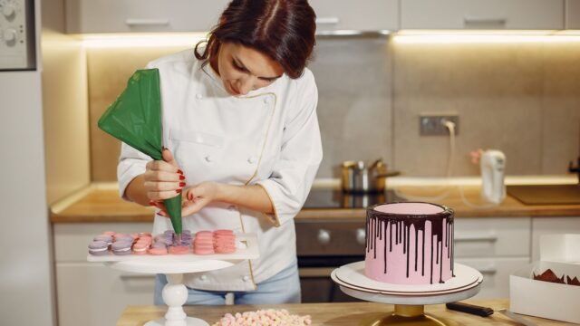 Herbruikbare spuitzak: banketbakster spuit crème met een groene spuitzak naast een drip cake