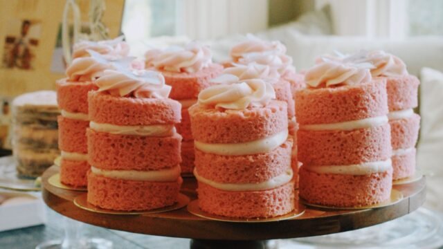 Houten taartplateau: roze mini cakejes op een donker houten taartplateau op voet