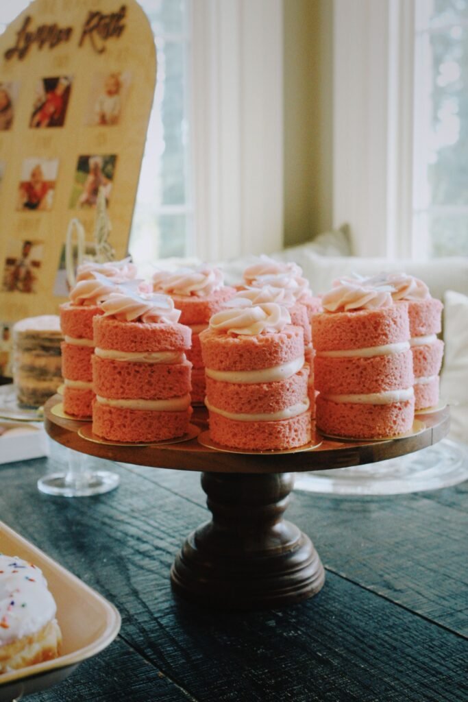 Houten taartplateau: roze mini cakejes op een donker houten taartplateau op voet