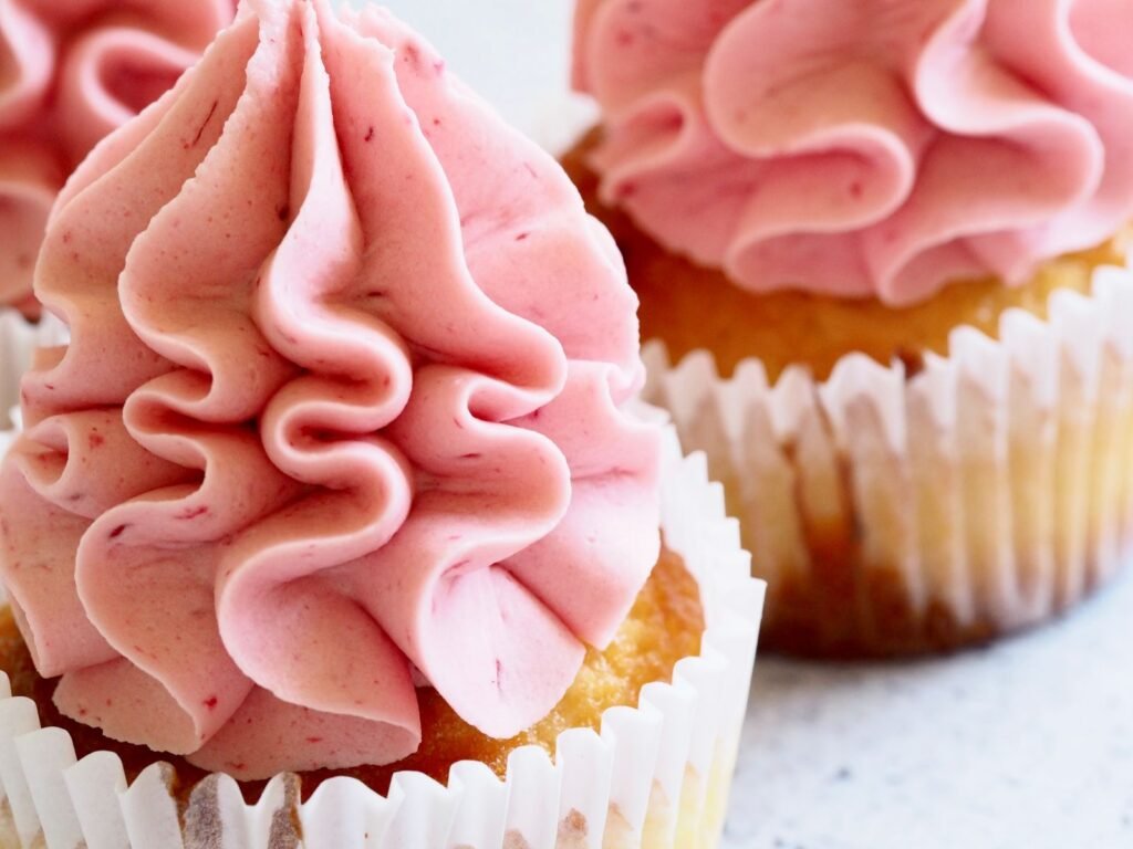 Kartelspuitmondje gekruld: cupcakes met gekrulde roze botercrème rozetten