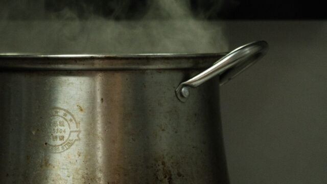 Katoenen spuitzak koken: dampende rvs kookpot met kokend water op het vuur