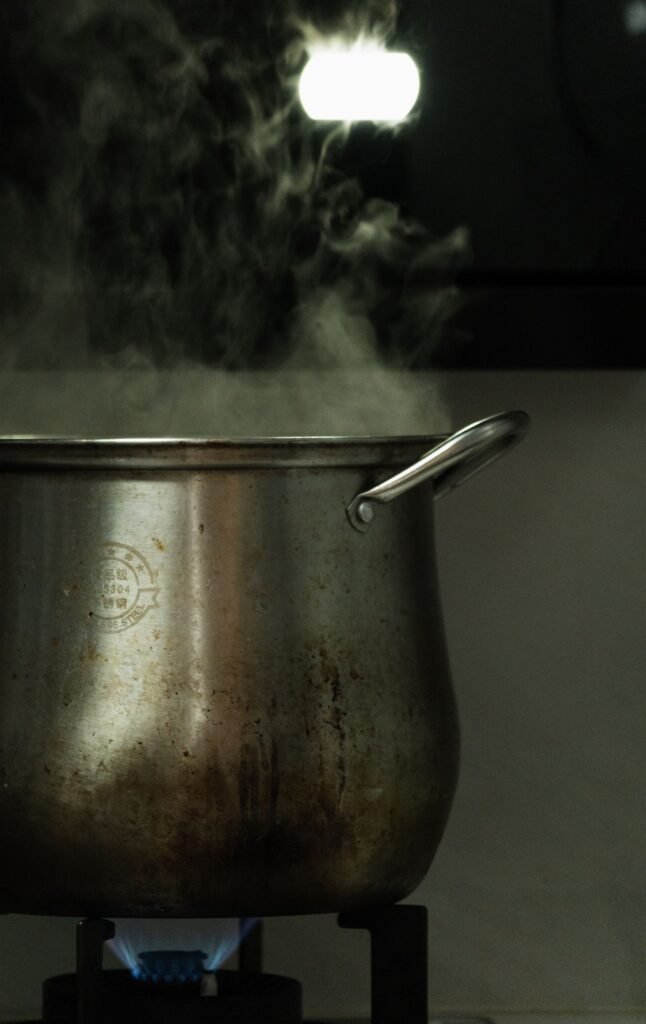 Katoenen spuitzak koken: dampende rvs kookpot met kokend water op het vuur