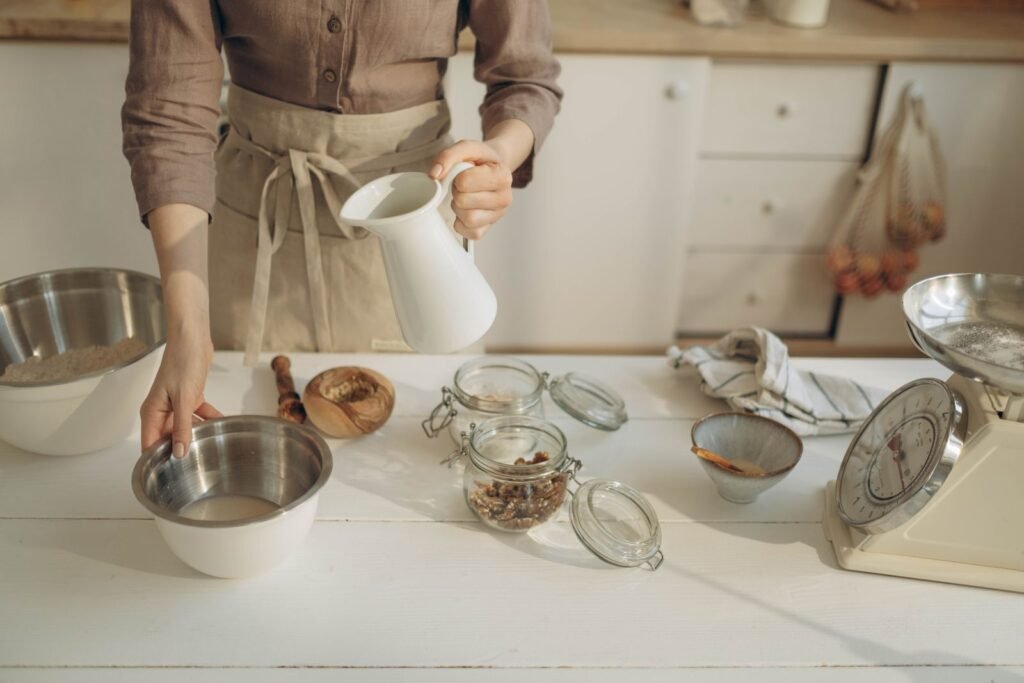 Keukenweegschaal tot 10 kg: vrouw giet melk in een kom tussen bakingrediënten met een weegschaal ernaast