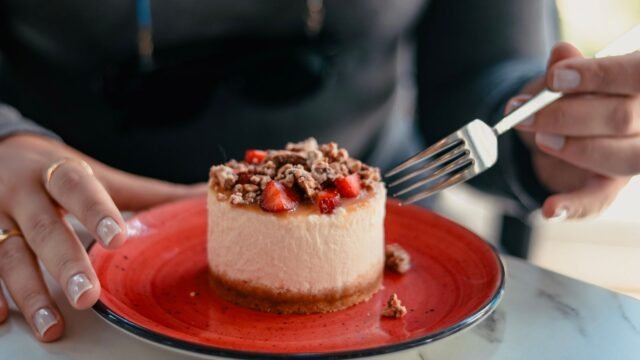 Mini springvormpjes set: individuele mini-cheesecake met aardbeien en noten op een rood bord