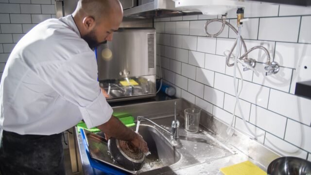 Siliconen spuitzak schoonmaken: kok wast keukengerei af in een rvs gootsteen