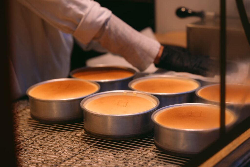Springvorm lekdicht: bakker haalt versgebakken cheesecakes in ronde vormen uit de oven