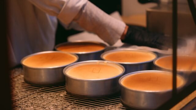 Springvorm lekdicht: bakker haalt versgebakken cheesecakes in ronde vormen uit de oven