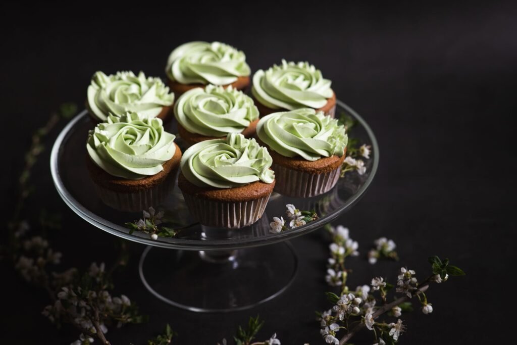 Spuitmondje gras maken: cupcakes met groene botercrème op een glazen taartplateau