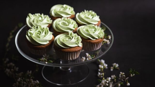 Spuitmondje gras maken: cupcakes met groene botercrème op een glazen taartplateau