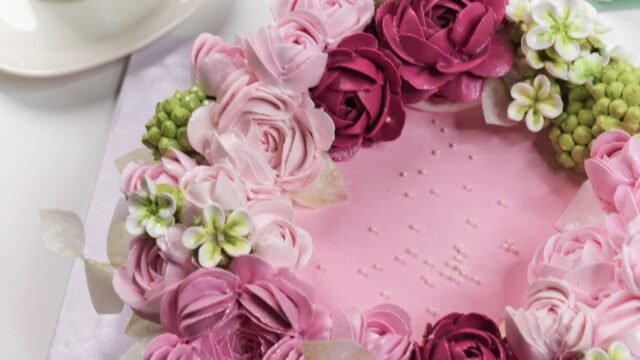 Spuitmondje roos maken: roze taart met een krans van gespoten botercrème rozen