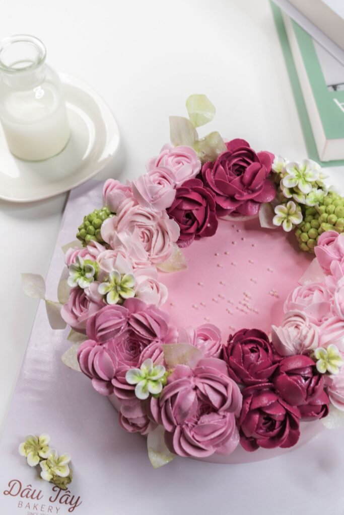 Spuitmondje roos maken: roze taart met een krans van gespoten botercrème rozen