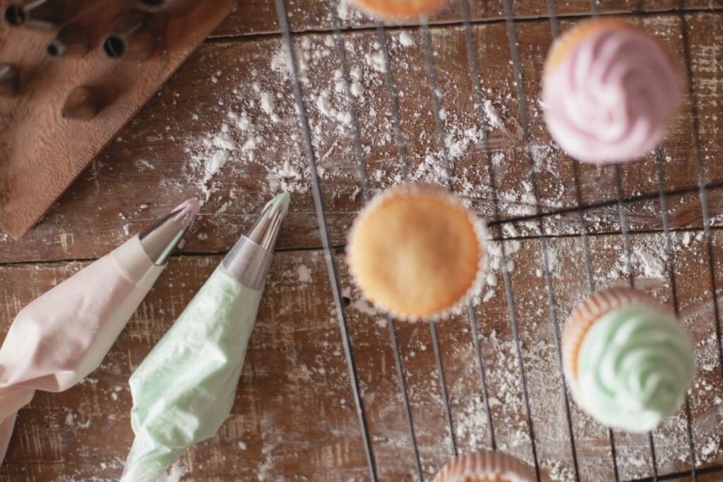 Spuitmondje ster 1M: cupcakes met gespoten rozetten en spuitzakken op een afkoelrooster
