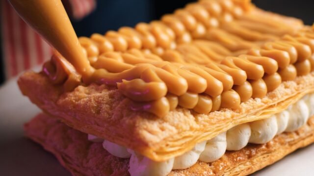 Spuitmondjes set taart: banketbakker spuit crème in toefjes op een gelaagd gebak