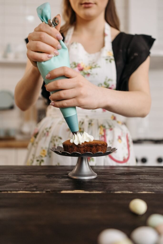 Spuitzakken gebruiken: vrouw spuit botercrème met een spuitzak op een taartje