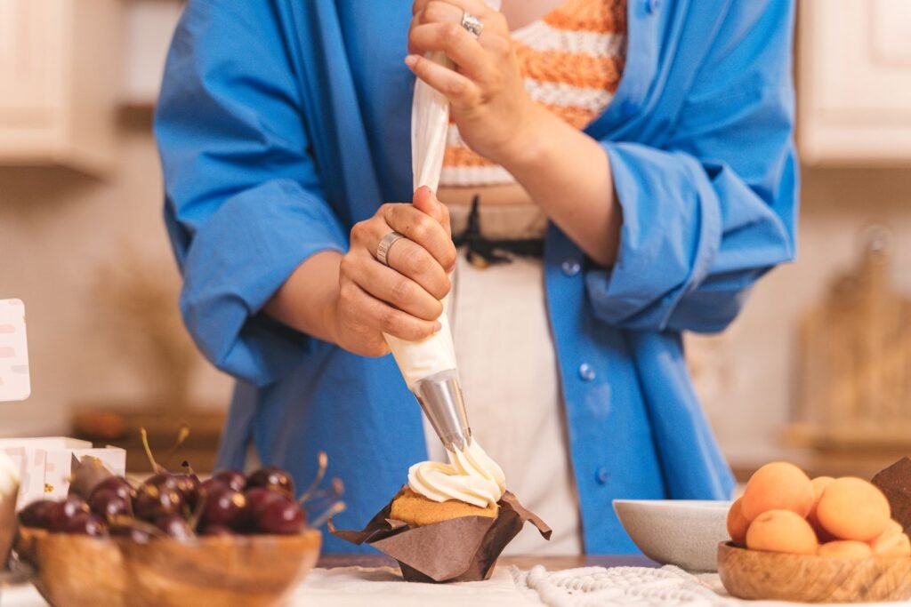 Stevige spuitzakken Aveve: man spuit slagroom met een spuitzak op een cupcake in de keuken