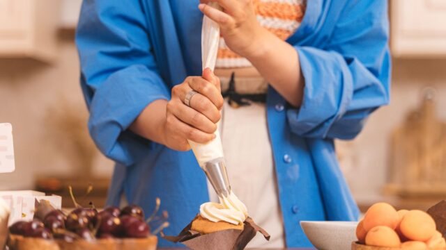 Stevige spuitzakken Aveve: man spuit slagroom met een spuitzak op een cupcake in de keuken