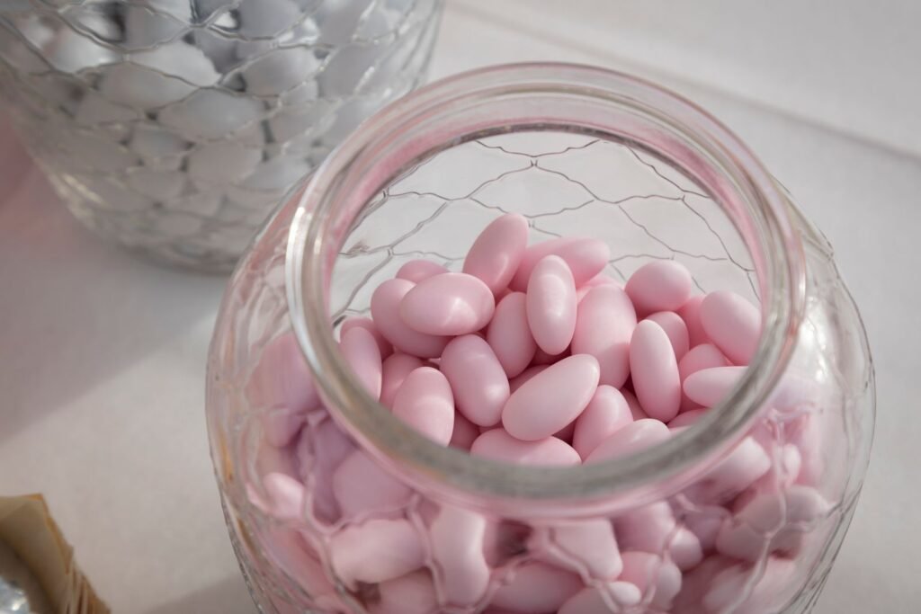 Suikerbonen kopen online: glazen pot met roze suikerbonen en witte suikerbonen op de achtergrond