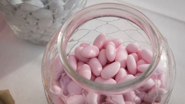 Suikerbonen kopen online: glazen pot met roze suikerbonen en witte suikerbonen op de achtergrond