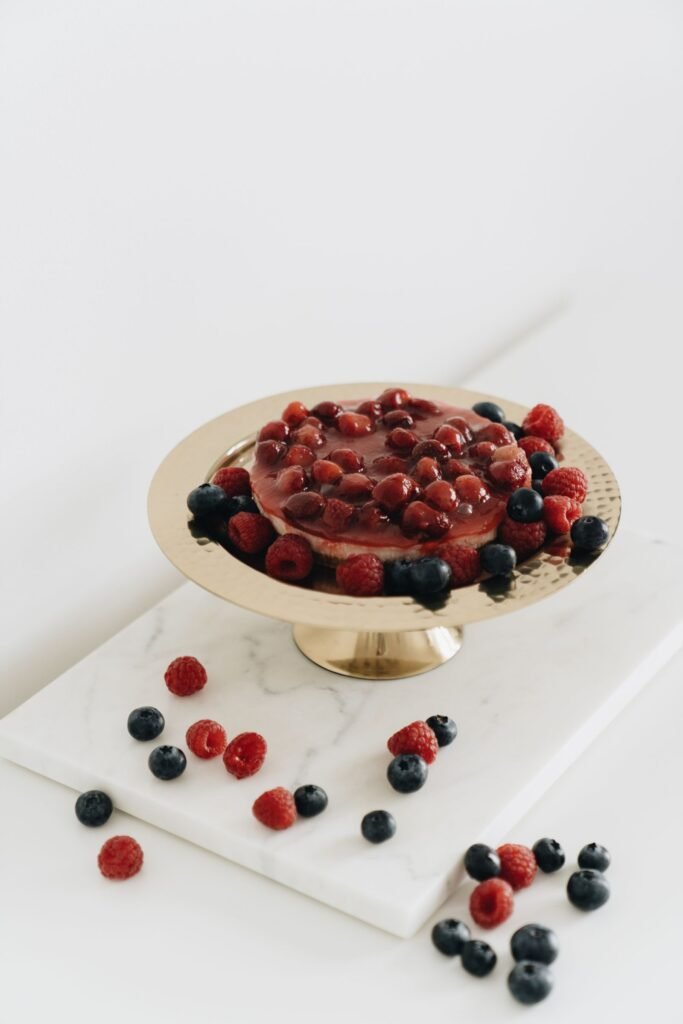 Taartplateau goud: cheesecake met rode bessen op een gouden taartplateau op voet