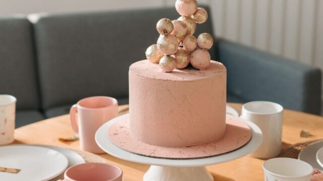 Taartplateau keramiek: roze verjaardagstaart op een wit keramisch taartplateau op een gedekte tafel