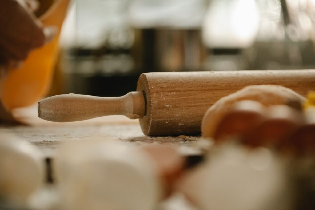 Verstelbare deegroller hout: houten deegroller op een met bloem bestoven tafel naast deeg
